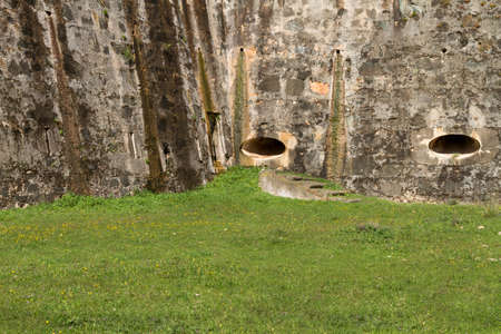 Empty grass ground against ancient stone wallの写真素材