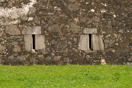 Stone ancient facade windows with front grass groundの写真素材