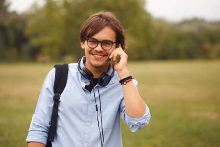 Portait of a young model talking on a smart phone in public park.の写真素材