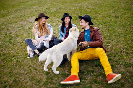 A group of people sitting on the green grass. They laugh and smile. Friendly atmosphere on nature background. Horizontal viewの写真素材