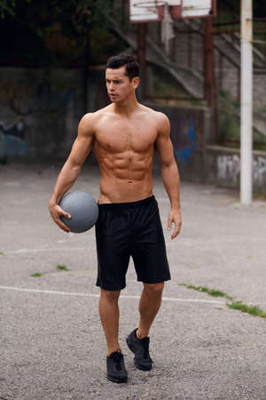 A fit, strong, muscular caucasian brunette young man shirtless outside.の写真素材