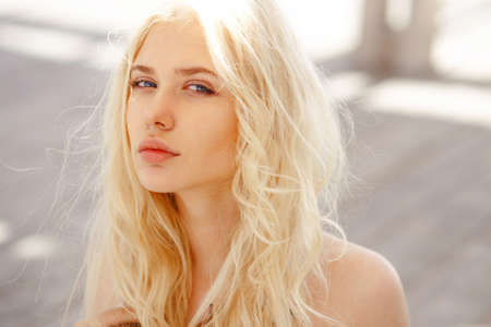 Portrait of a cute blonde with angelic blue eyes,curl hair and big lips look innocent at camera. Horizontal view on wooden floor background.の写真素材