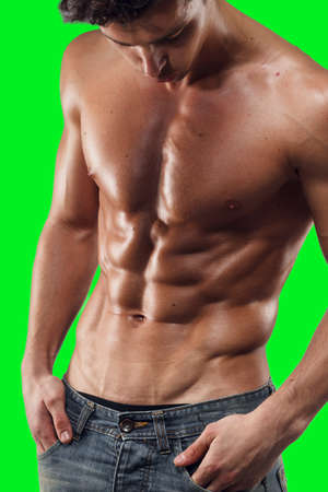 Closeup of a shirtless sexy man in jeans, posing hot in studio, showing a six pack abs, of a green screen chrome key background.の写真素材