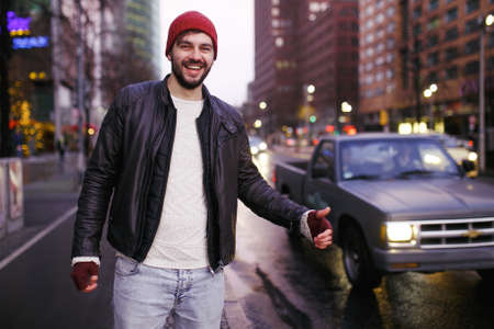 Young handsome hipster young man traveler hitchhiking along on road in the city.
