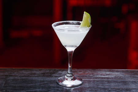 Margarita cocktail with salted rim, fresh lime and lime juice, cold summer citrus refreshing drink or beverage with ice, on a counter bar.の写真素材