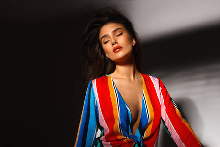 Frontal beauty portrait of a sexy young woman with makeup and a fashionable hairstyle, have closed eyes, poses in studio on shadow background.の写真素材