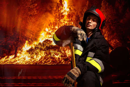 Fireman in action with hatchet, have operation to extinguish the flame in forest.