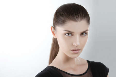 Beauty portrait of a natural skin of a young fashion model, in black dress, looking at camera, over...