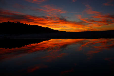 Orange sky background. Female hands in the form of heart on twilight and pink skyの写真素材