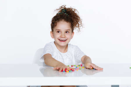 Smiling cute little girl dressed in white with arranged hair up, over white background. Little girl...
