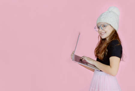 Happy little girl holding using laptop looking at computer, user, isolated on pink studio background.の写真素材
