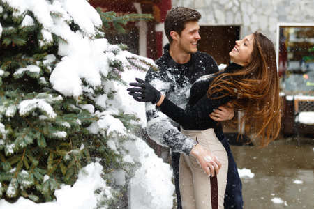 Loving young couple in winter clothes hugging and smiling outside, in a small town in Italy. horizontal image, winter view.の写真素材