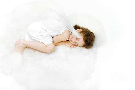 Charming sleeping little girl angel on soft white fur stand near arrow and arc, cupid, Valentines day , Xmas concept, isolated on white background. Horizontal view.の写真素材