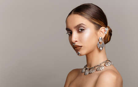 Beauty portrait of young woman with big lips, looking at camera. Gorgeous female model with silver jewelery.の写真素材