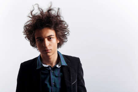 Portrait of a sad man with neglected hair, looks at the camera, dressed in shirt and jacket, over white background.の写真素材