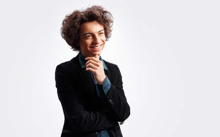 Curly haired young man on white background smiling.の写真素材