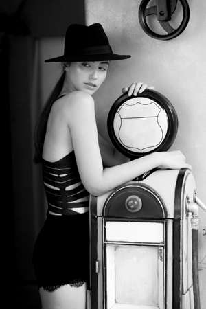 Beautiful brunette girl in a black bodysuit and hat, in retro decor.の写真素材