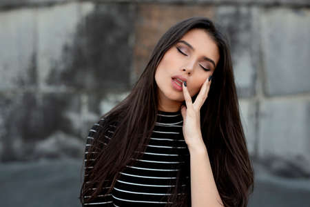 Beauty portrait of a sensual, dreaming girl with straight brunette hair, dressed in modern clothes, with makeup.の写真素材