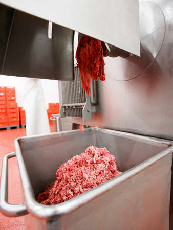 Horizontal view. Raw meat minced in an industrial process factory stored in a stainless steel crate...