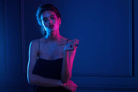 Frontal view of a sensual woman with bare shoulders over dark purple neon lights.