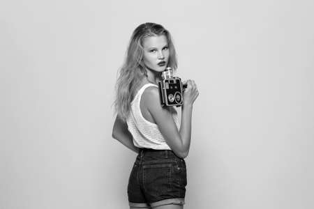 Beauty people. Woman holding vintage film camera on white background. Indoor. Black and white color.の写真素材