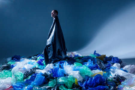 Man in studio, surrounded by empty plastic garbage bags. Content with ecological problems. Copy space.の写真素材