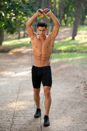 Frontal view of a athlete handsome guy in sportwear doing exercise outside in park. Healthy lifestyle concept.の写真素材