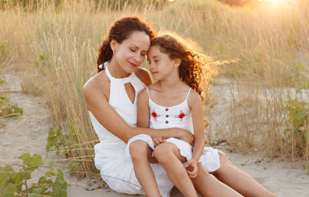 Mother hug daughter on the sea beach. Happy family in vacation and travel. Mom hug tender her...