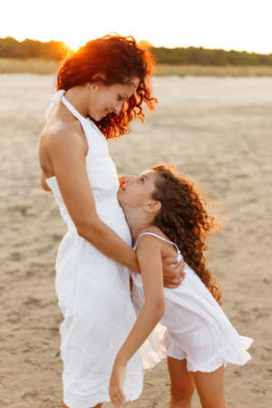 Happy family in vacation and travel. Mom hug tender her daughter outside at the sunset.の写真素材