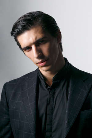 Frontal portrait of a business man dressed in black suit against a dark background.の写真素材