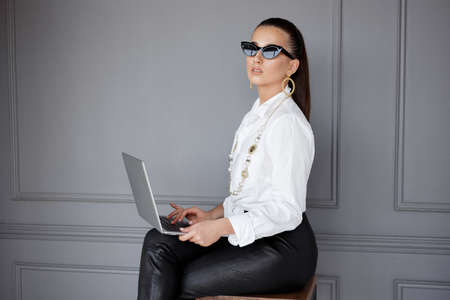 Confident business woman with make-up, looking at the side, over grey background. Copy space. Horizontal view.の写真素材
