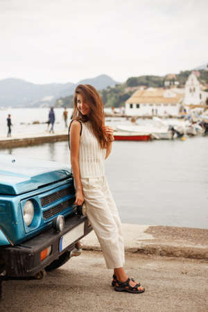 Cheerful girl standing near car outside. Traveler content.の写真素材