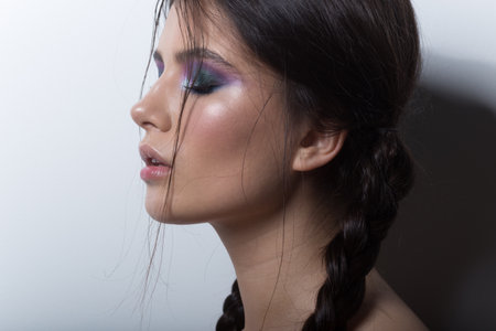 Beautiful brunette girl with braids and bright makeup, has got closed eyes, isolated white...