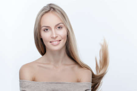 Beautiful smiling model with perfect skin, bare shoulders looking at camera. Girl with long hair on...