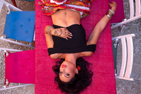 Top view of a sexy, slim brunette girl like a gipsy lying down at wooden table.