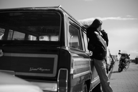 Black and white photo outside. Back view of a hipster girl with hair blowing.の写真素材