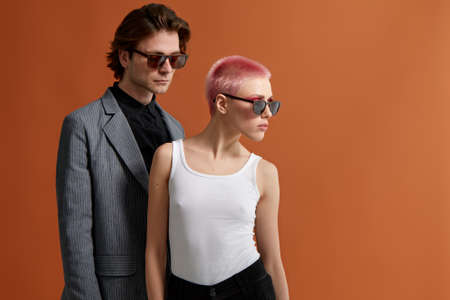 Stylish young hipster couple in sunglasses, posing together on a brown background. Profile portrait.の写真素材