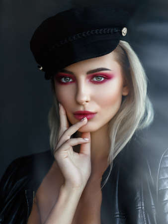 Sensual girl in black leather jacket and blonde hair in rock style on black background. Makeup, cosmetics, pink color.の写真素材