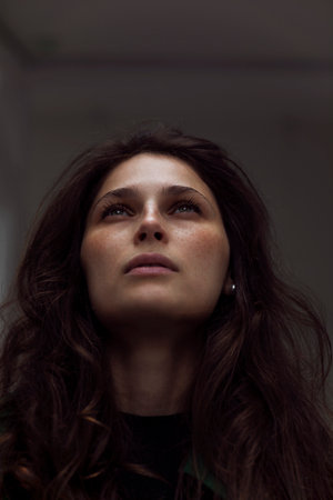 Closeup portrait of a beautiful woman with curly red hair against gray background.の写真素材