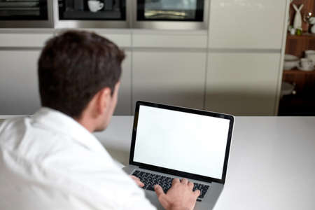 Frame view of man in casual clothes using a laptop while sitting at the table in office.の写真素材