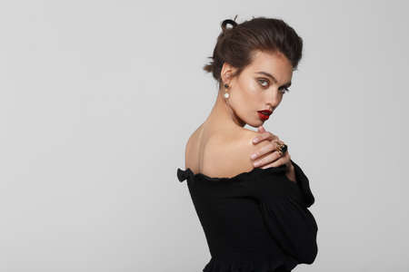 Attractive model with makeup and hairstyle in black dress, wears luxury jewellery, over white background.の写真素材