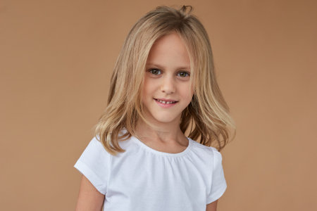 Close-up front portrait of pretty little girl with wavy blond hair.の写真素材