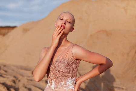 Front portrait of a beautiful young woman posing in the desert, with closed eyes, covered her face with her hand.の写真素材