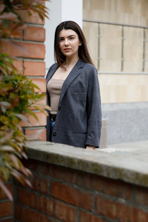 Portrait of a young beautiful caucasian woman with urban style near rough stone wall, looking at camera.の写真素材