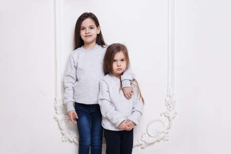 Gorgeous two caucasian sisters posing together on white background, smiling and looking at camera.の写真素材