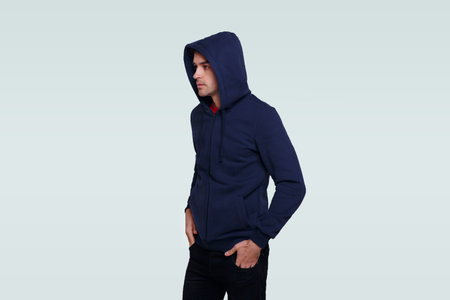 Portrait of a young man in green jumper and jeans, with a hood on his head, isolated wjhite background.の写真素材