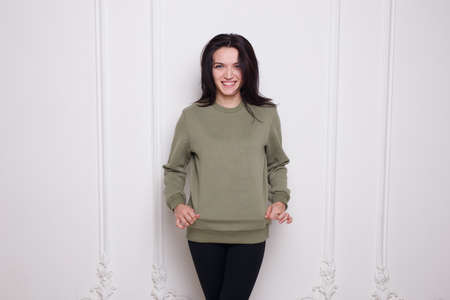 Smiling young woman brunette in a geen sweater, looking at camera, isolated on white background. Space copy.の写真素材