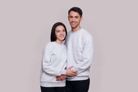 Couple standing embraced and smiling on white background.の写真素材