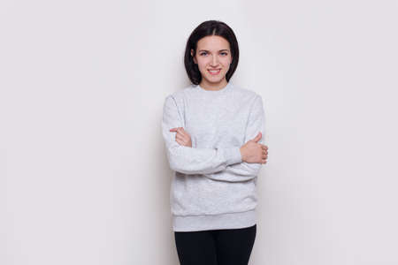 Smiling young woman brunette in a light grey sweater, isolated on white background. Space for text. Horizontal view.の写真素材
