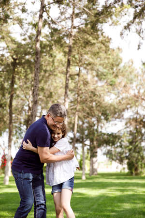 Grandpa hugs his niece in the park on a sunny day.の写真素材